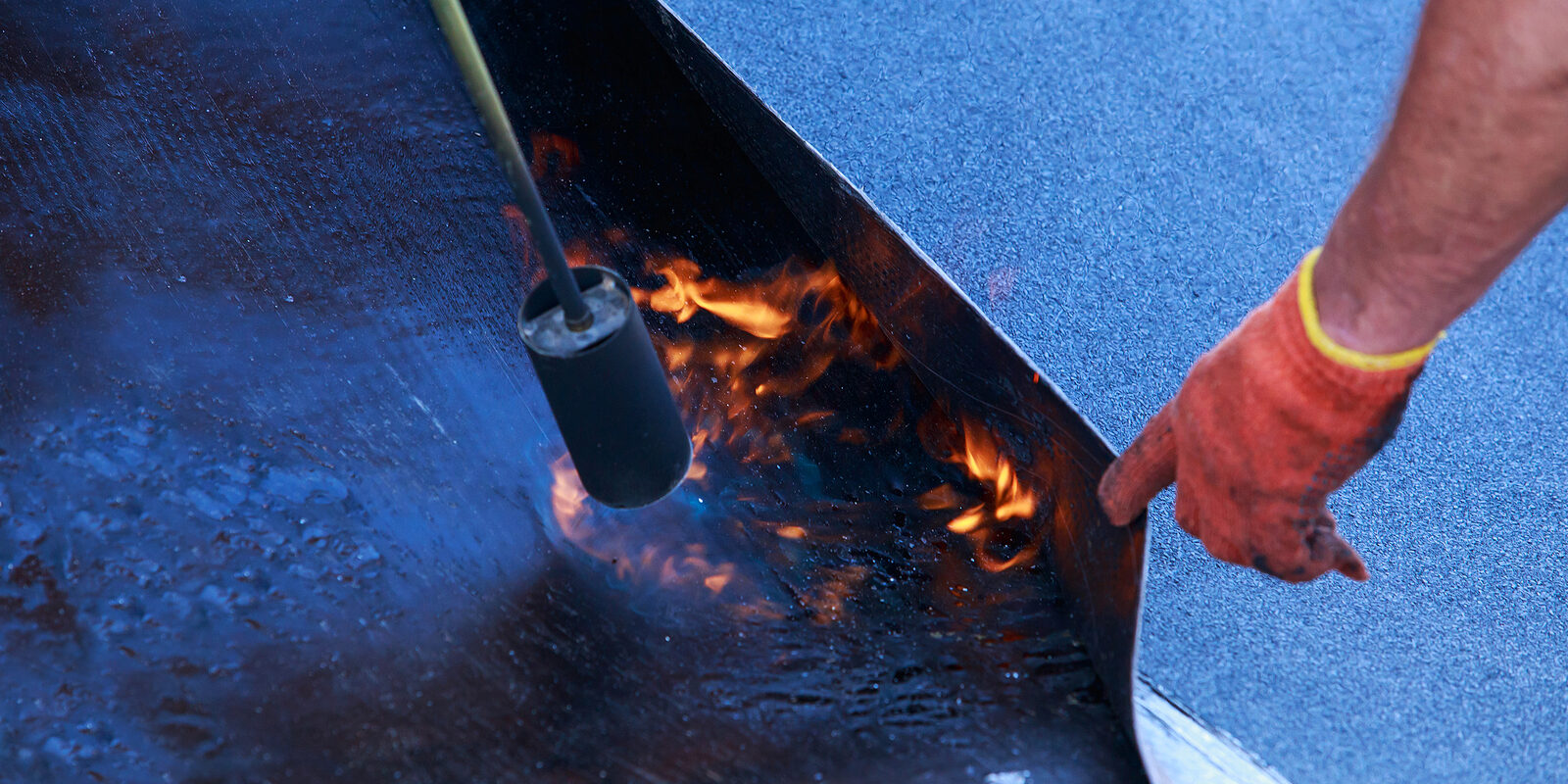 Gas burner with fire on the background of roofing material